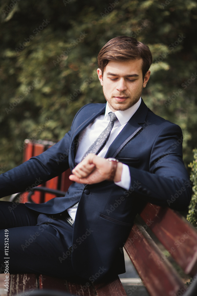 Confident businessman looking on his wrist watch in suit Confident businessman looking on his wrist watch in suit