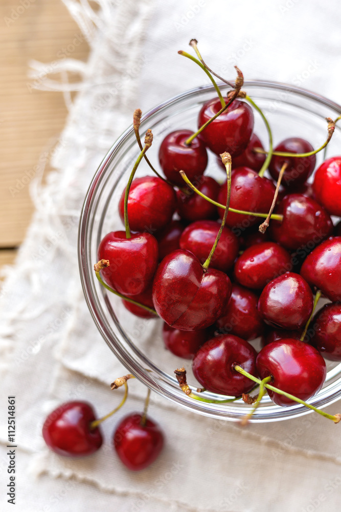 Fresh juicy sweet cherries in glass bowl. Rustic background with homespun napkin. Fresh juicy sweet cherries in glass bowl. Rustic background with homespun napkin.