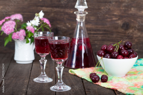 Cherry liqueur in glasses and bowl with sour cherries 