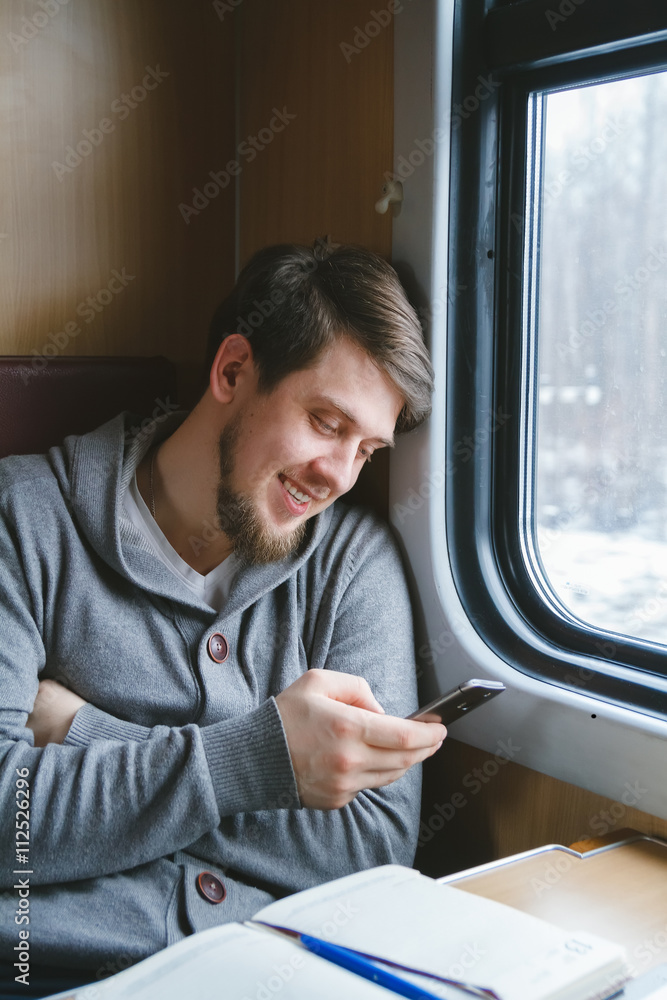 The man sits at a table in a train, writes sms
