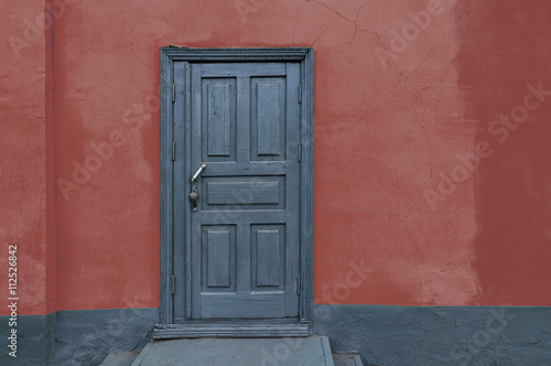 Rustic vintage old house red wall with gray wooden door