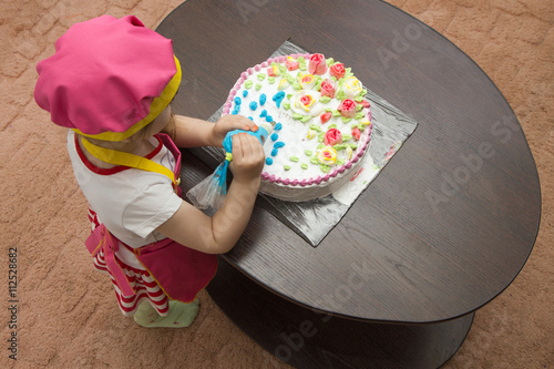 Little girl children decorate cream cake