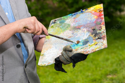 Professional palette in male painter's hand outdoors