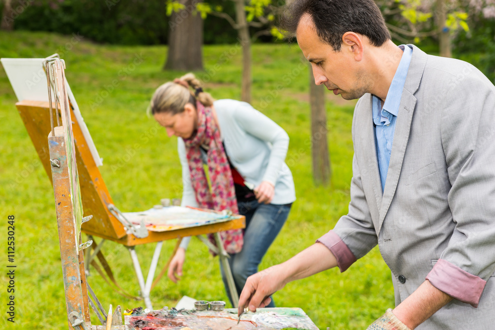 Two fashionable creative painters during an art class in a park Two fashionable creative painters during an art class in a park