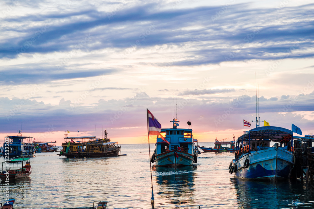 Sunset over a row of fishing boats on Koh tao beach in Thailand