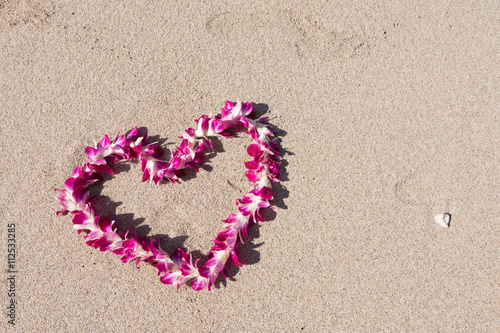 orchid flower garland necklace in love heart shape on white sand beach, romantic couple honeymoon trip at Hawaii 
