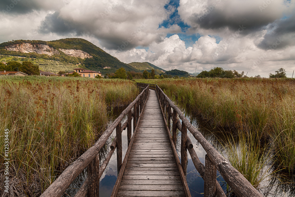 Wooden Bridge on the Lake under a Sky Full of Clouds