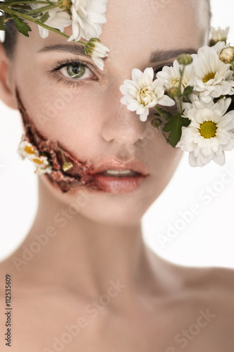 Beauiful girl with huge wound on cheek and flowers covering face