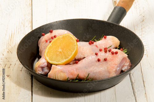 raw chicken drumstick with red peppercorn, lemon slice and rosem photo