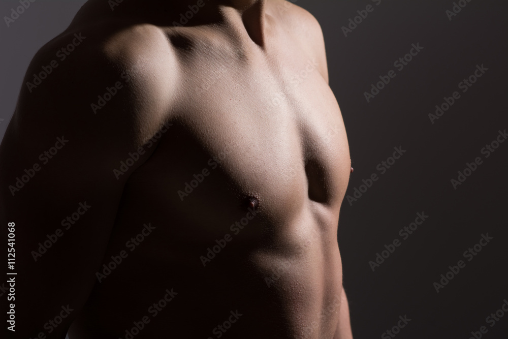 Close up of a sports man's chest. Muscular man on a dark background