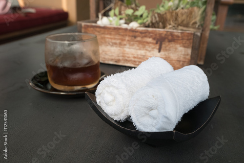Foto white scented rolled wet towel and cold drink to welcome a guest to Thai aroma massage resort spa, Thailand