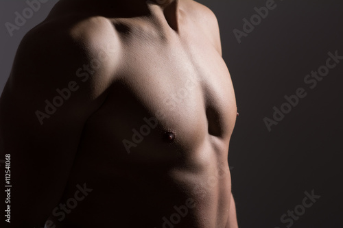 Close up of a sports man's chest. Muscular man on a dark background