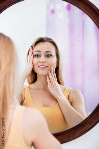 Woman having a look at her face at the mirror