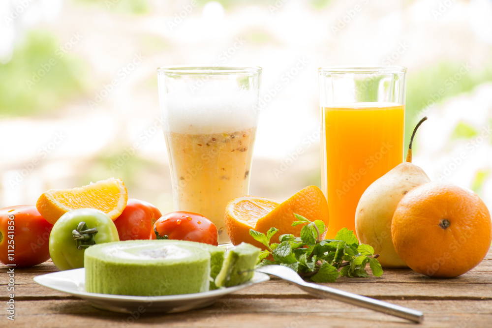 Fototapeta premium Background fruit have tomato and orange and juice with green tea cake.On wooden background outdoor view and holiday with relax 