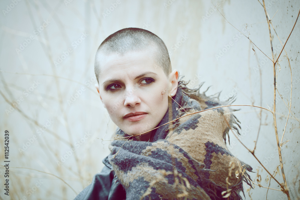 Portrait of sad beautiful Caucasian white young bald girl woman with shaved  hair head in leather jacket and scarf shaw looking away, toned with Instagram  filters in blue green color Stock-Foto