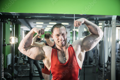 man is engaged in fitness bodybuilder posing shows biceps and smiling