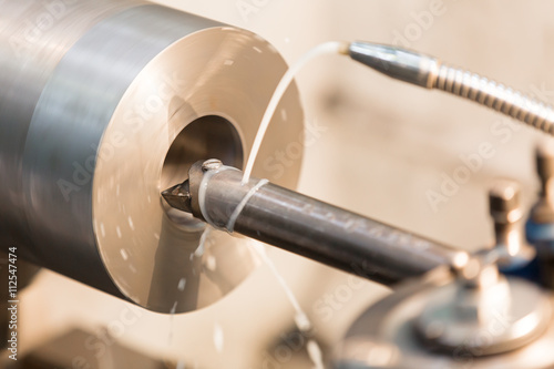 Fotografi Hole cutting by boring tool on lathe turning machine with cooling lubricant conc