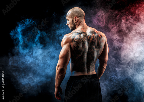 Back view of tattoed muscular man posing. Looking sideways