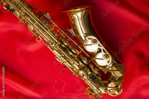 beautiful golden saxophone on delicate red silk background