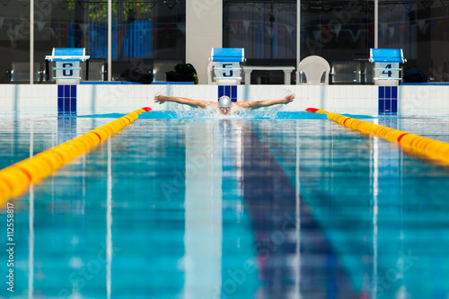 dynamic and fit swimmer in cap breathing performing the butterfly stroke