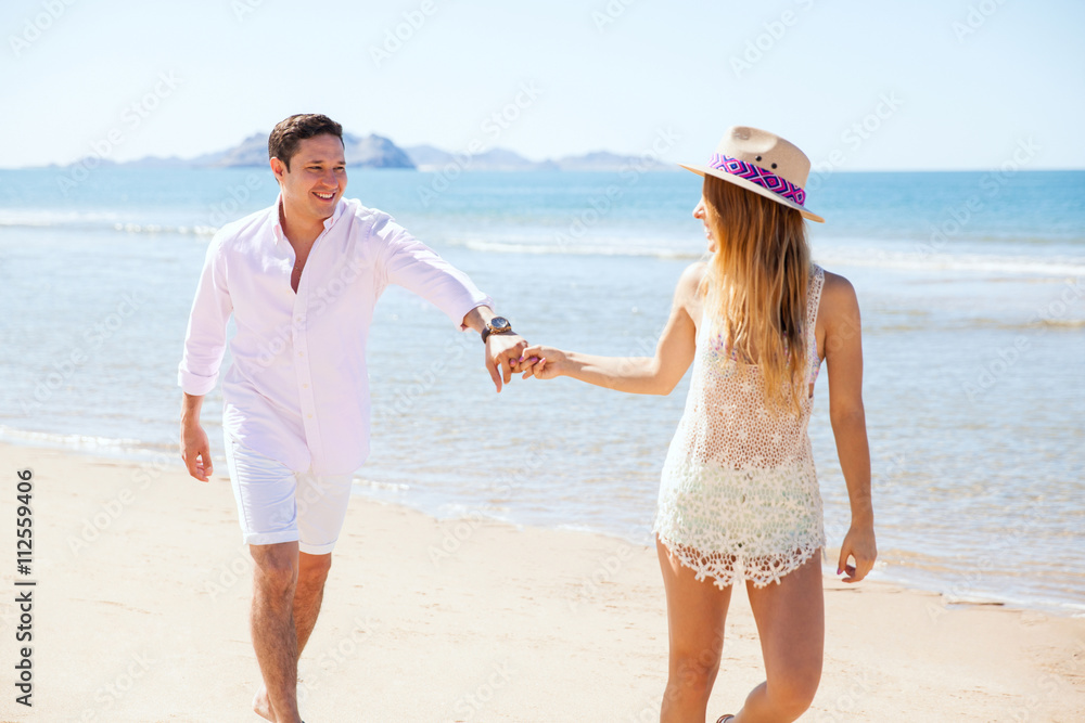 Woman pulling her boyfriend for a run at the beach