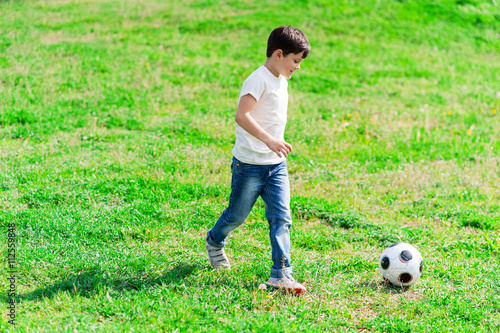 Pretty male kid is playing with ball