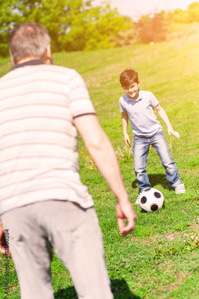 Cheerful old man and grandson entertaining in park