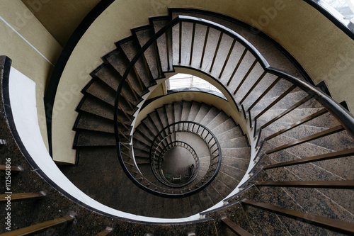 Spun circular staircase with a handrail in a building without people.