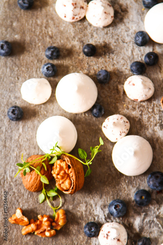 meringue pavlova cake with fresh blueberries and walnuts on dark