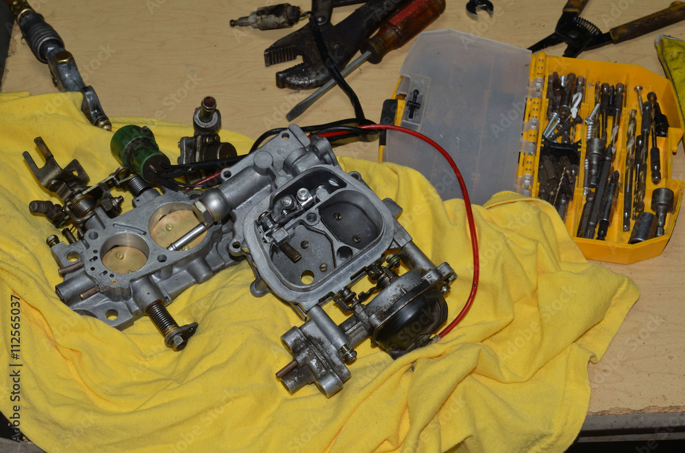 Truck vehicle carburetor taken apart and spread out on a worktable with