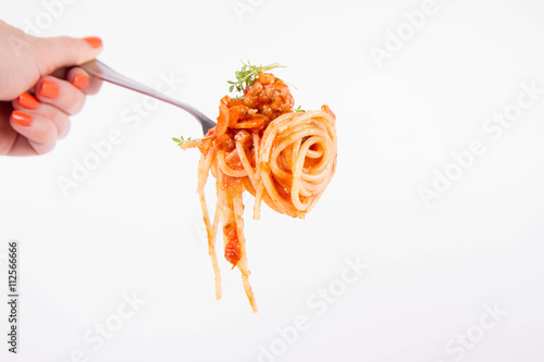 Spaghetti bolognese with garlic on a fork held by a woman's hand