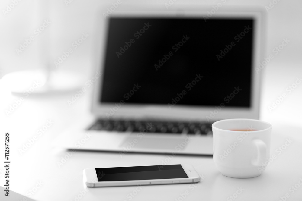 Workplace with laptop, mobile phone and cup of coffee indoors Workplace with laptop, mobile phone and cup of coffee indoors