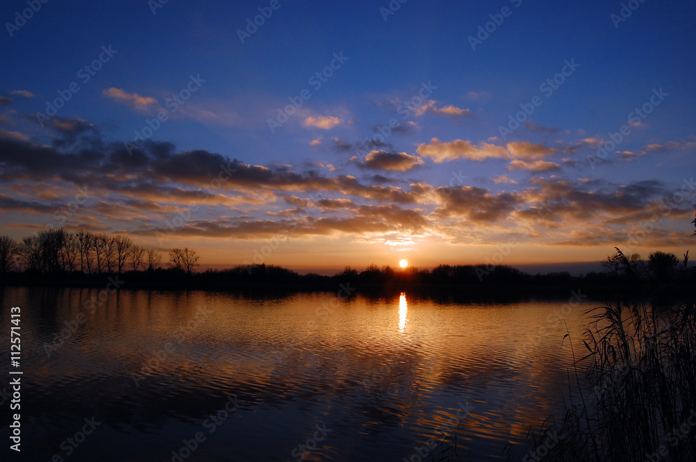 Sunset over the lake, clouds reflected in the water