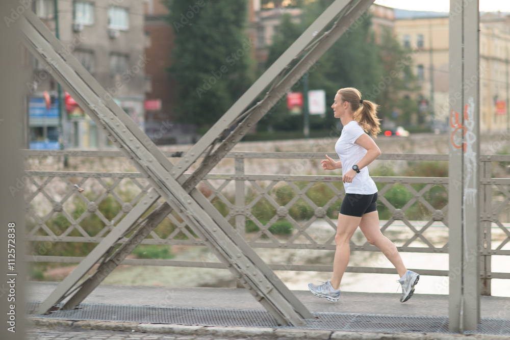 sporty woman running  on sidewalk