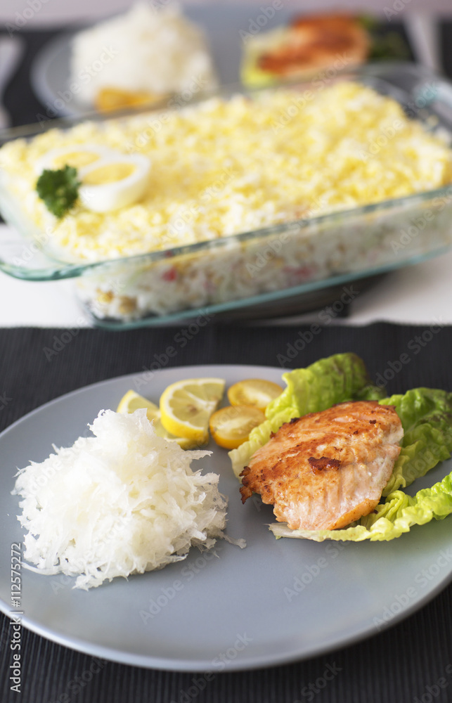 Fish atlantic salmon with salad and grated radish. The main meal for dinner with fish on the blue plate. Fish atlantic salmon with salad and grated radish. The main meal for dinner with fish on the blue plate.