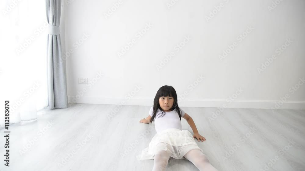 Funny Asian girl in ballet costume sliding on floor at home. Funny Asian girl in ballet costume sliding on floor at home.