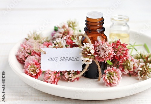  Cosmetic bottle of aroma oils extract  clover flowers  paper tag handwritten text organic. Herbal skincare. 