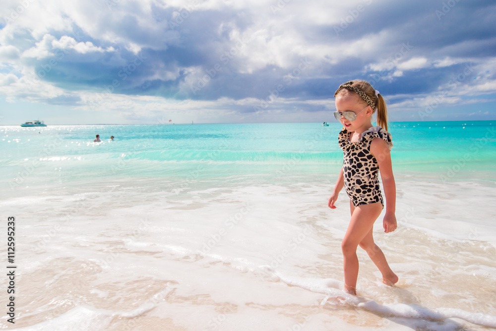 Adorable little girl have fun at shallow water on white beach Adorable little girl have fun at shallow water on white beach