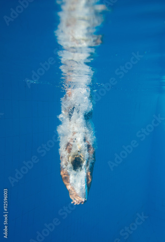 Diving straight down. Underwater shot of a professional diver entering the water