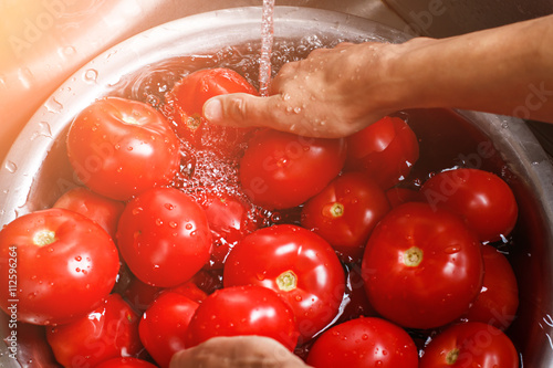 Male hands wash big tomatoes. Basin with tomatoes and water. Time to cook soup. Ripe and juicy. © DenisProduction.com