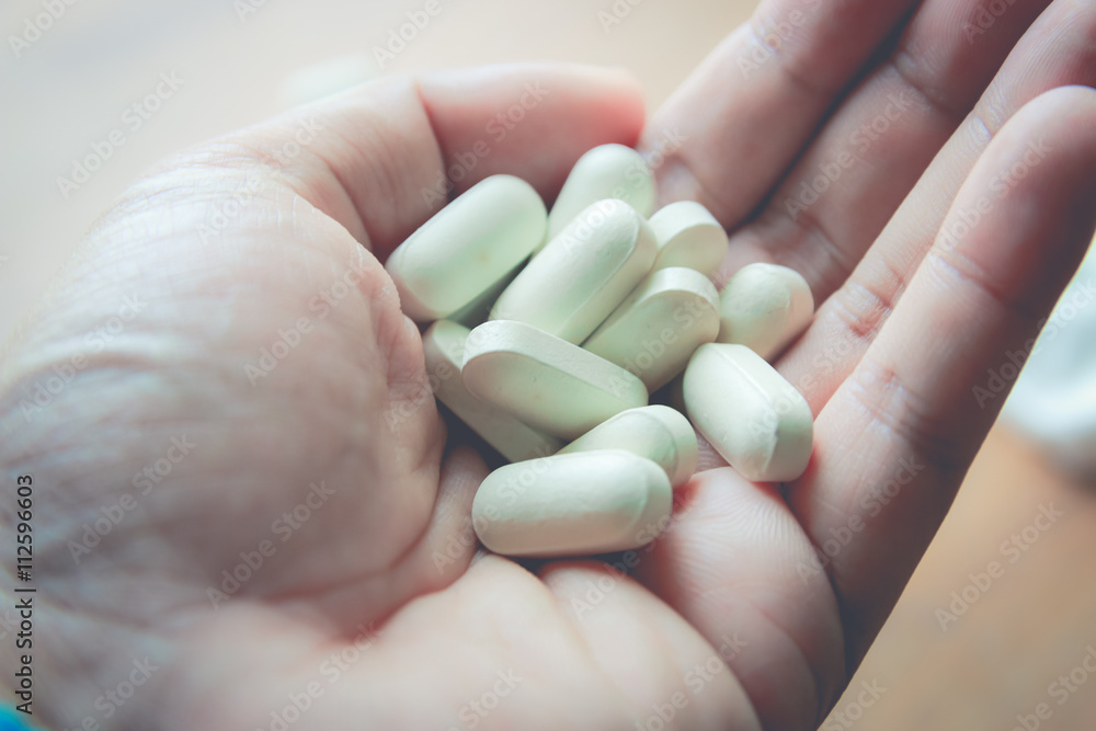 medicine pill on hand with wood table background medicine pill on hand with wood table background