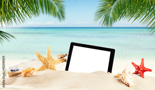 Empty tablet on sandy beach with copypsace photo