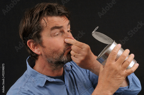 Homme ayant ouvert une boîte de conserve nauséabonde  photo