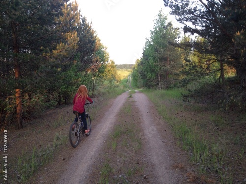 Fototapeta Naklejka Na Ścianę i Meble -  девочка едет на велосипеде по лесной дороге
