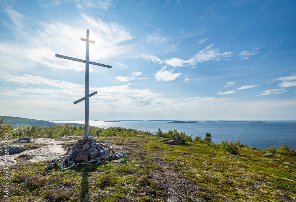 Christian wooden cross on top of the mountain, island in the white sea
