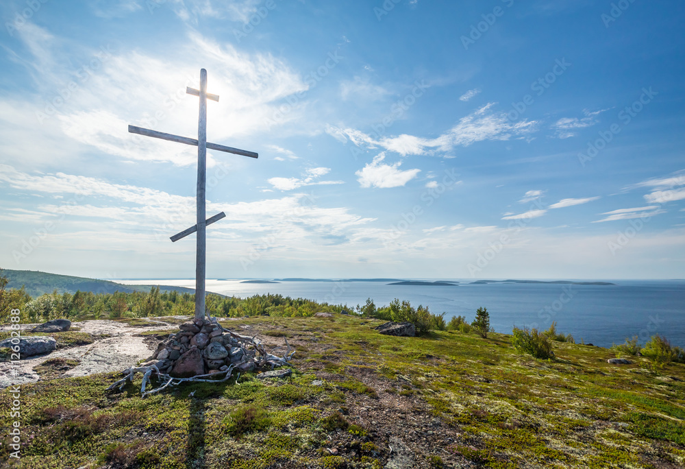 Christian wooden cross on top of the mountain, island in the white sea Christian wooden cross on top of the mountain, island in the white sea