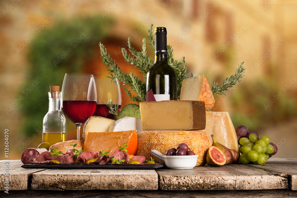 Delicious cheeses with wine on old wooden table.