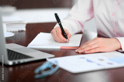 Closeup of a business woman writing in a notebook