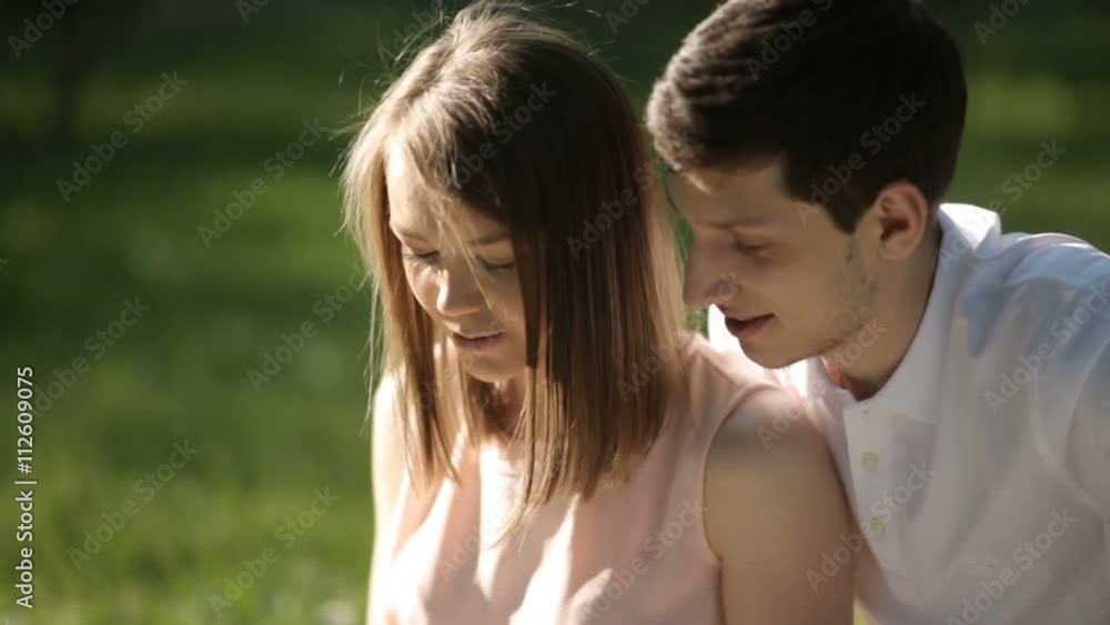 The guy with the girl sitting in the park and looking at tablet. Close-up. The guy with the girl sitting in the park and looking at tablet. Close-up.