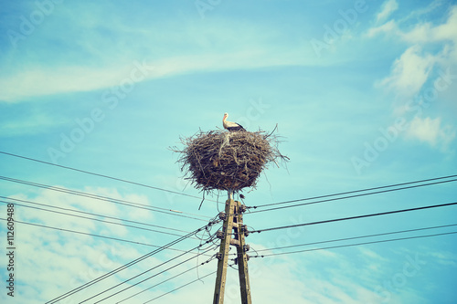Retro toned stork nest on a power line pole